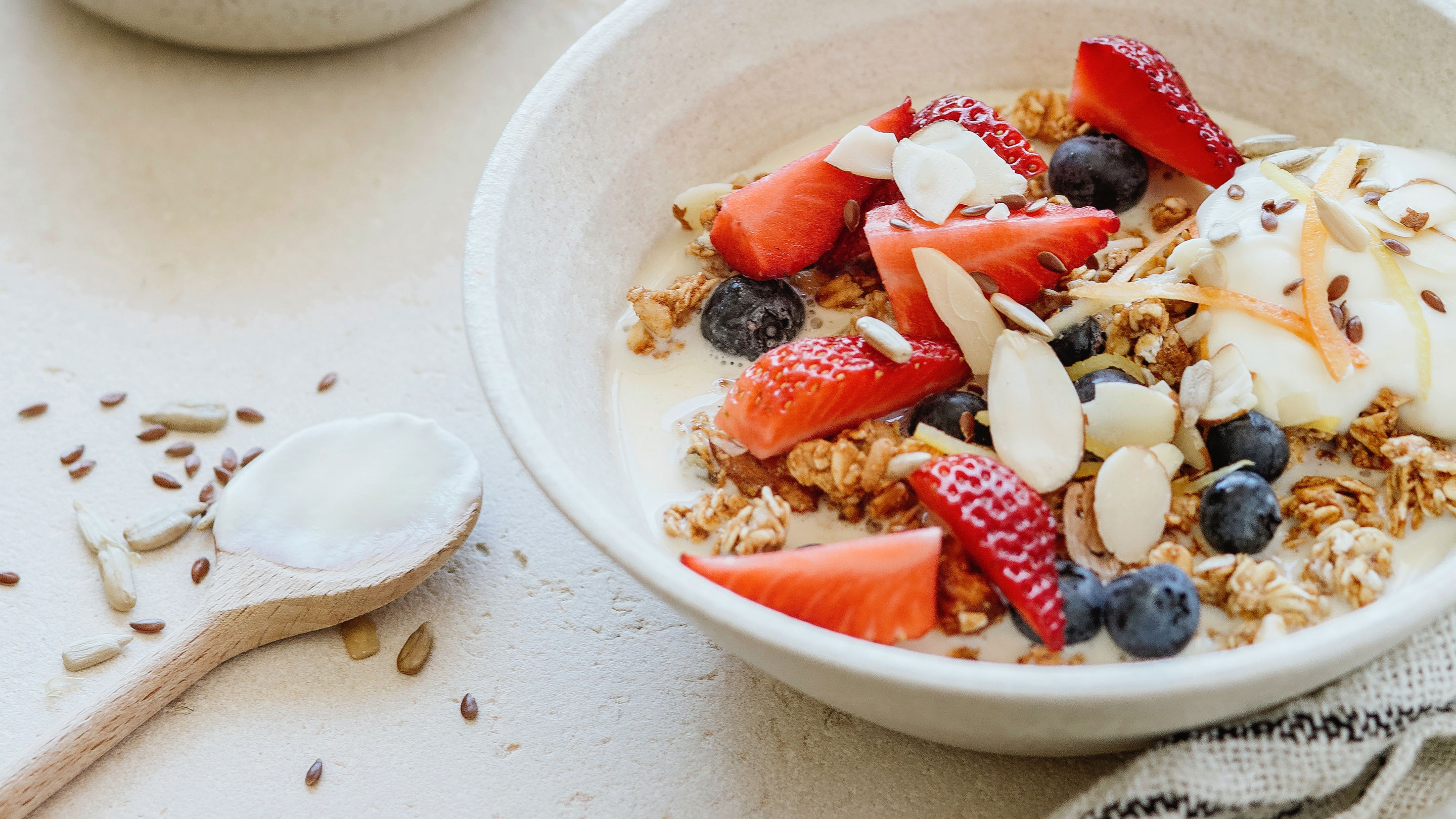 ein Müsli mit Leinsamen, Blaubeeren und Erdbeeren auf hellem Untergrund